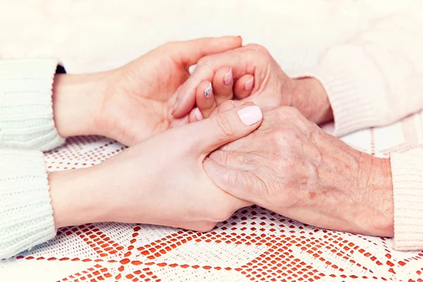 Mulher idosa com seu cuidador em casa. De mãos dadas, horizontalmente vista superior close-up . — Fotografia de Stock