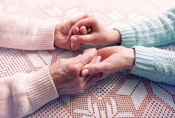 Seniorin mit ihrer Betreuerin zu Hause. Händchenhalten, horizontale Nahaufnahme von oben. — Stockfoto