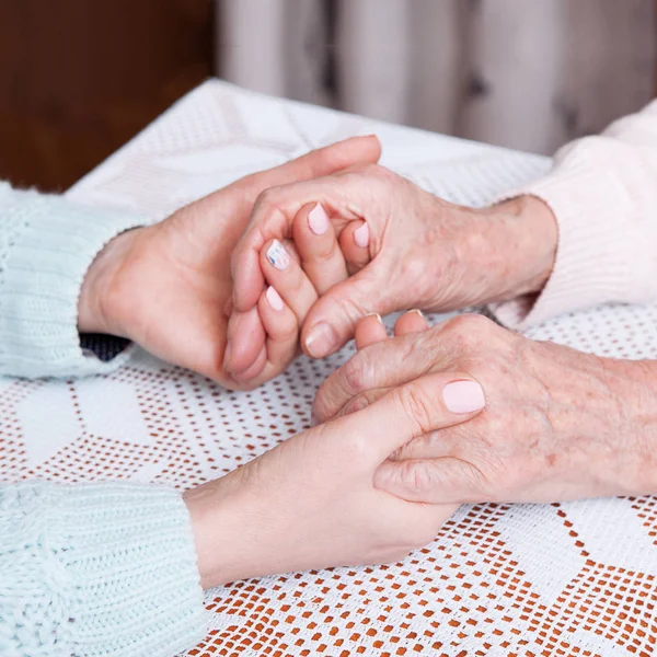 Een zorg is thuis voor ouderen. Bedrijf handen closeup — Stockfoto