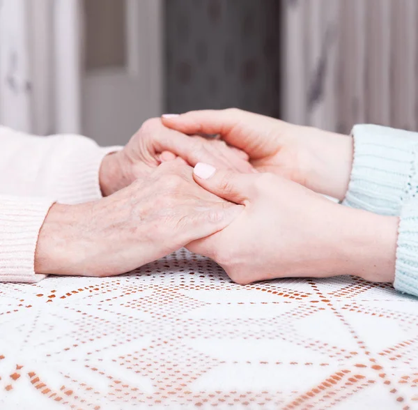 Senior woman with her caregiver at home. Holding hands, horizontally top view closeup. — Stock Photo, Image