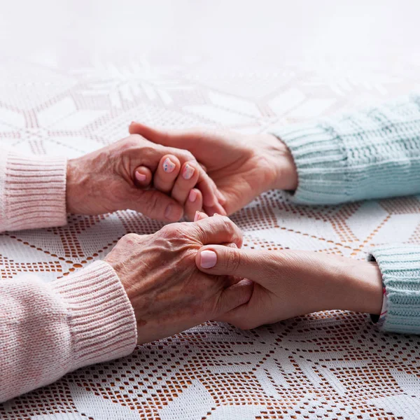 Um cuidado é em casa de idosos. Segurando as mãos close-up — Fotografia de Stock