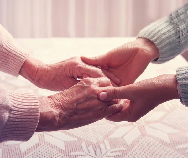 Femme âgée avec sa soignante à la maison. Tenant la main, vue de dessus horizontalement gros plan . — Photo