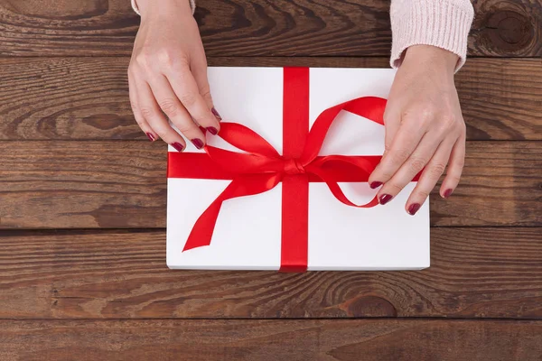 Woman holding presents gift box laid on wooden table background — Stock Photo, Image