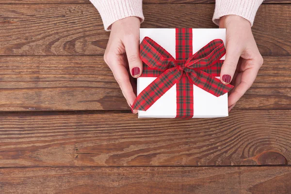 Mujer sosteniendo regalos caja de regalo colocada sobre fondo de mesa de madera — Foto de Stock