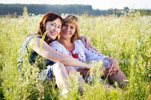 Glückliche Frauen mit Blume entspannen sich im Gras mit einer Blume. — Stockfoto