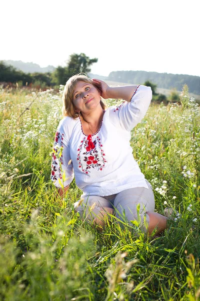 Happy woman with flower relaxes in the grass with a flower. — Stock Photo, Image