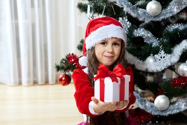 クリスマス、年末年始と人概念の祭典。自宅に飾られたクリスマス ツリーの近くに立ってボックス贈り物を持つ幸せな若い女の子 — ストック写真