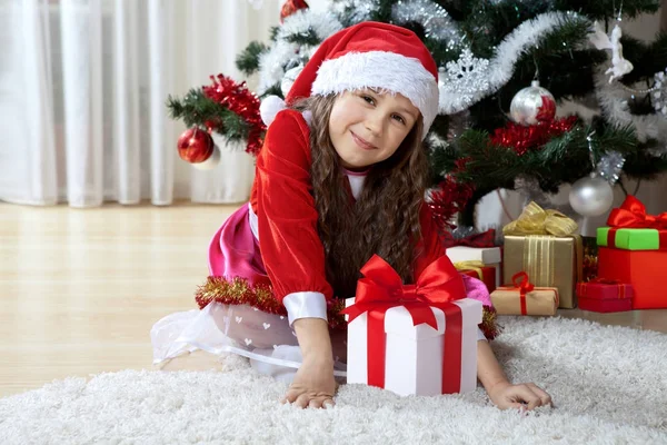 Święto Bożego Narodzenia, ferii zimowych i koncepcja ludzie. Szczęśliwa młoda dziewczyna z darów w polach siedzi w pobliżu urządzone choinki w domu — Zdjęcie stockowe