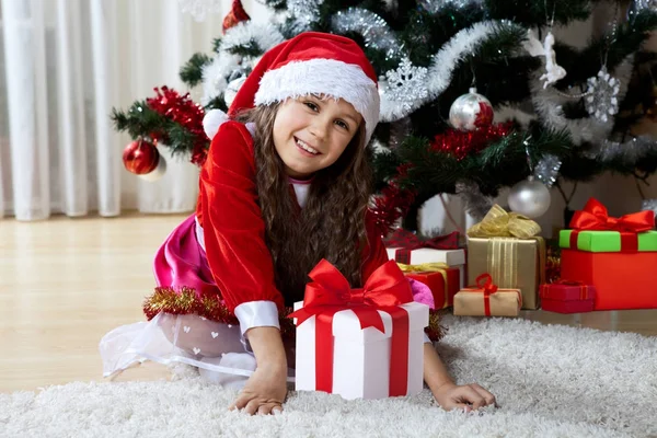 Celebração do Natal, férias de inverno e conceito de pessoas. Jovem feliz com presentes em caixas sentadas perto de uma árvore de Natal decorada em casa — Fotografia de Stock