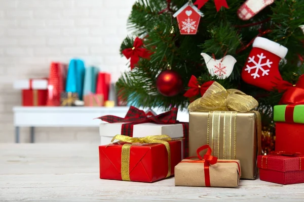 Mesa de madera blanca frente al colorido árbol de Navidad con cajas de regalo. Puede ser utilizado para mostrar o montar sus productos — Foto de Stock