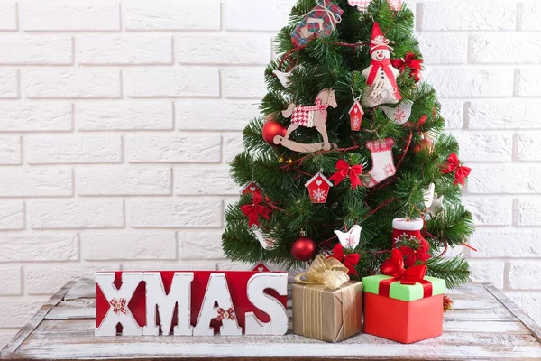 Mesa de madera blanca frente al colorido árbol de Navidad con cajas de regalo. Puede ser utilizado para mostrar o montar sus productos — Foto de Stock