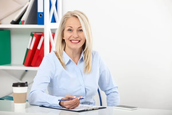 Business woman working in office with documents. Beautiful middle aged woman looking at camera with smile while siting in the office. — Stock Photo, Image