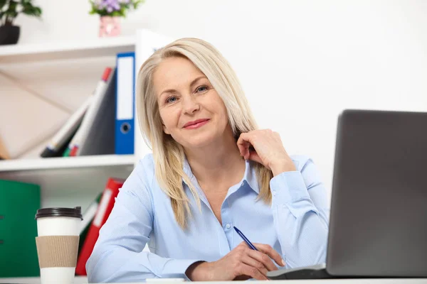 Haar werk is haar leven. Zakenvrouw in kantoor met documenten werken. Mooie midden leeftijd vrouw op zoek naar camera met glimlach terwijl aanbrengen in het kantoor. — Stockfoto