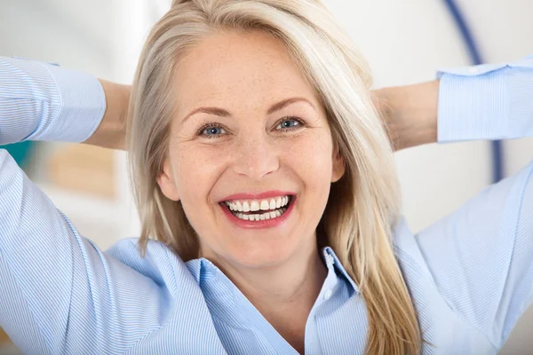 Mulher de negócios moderna. Mulher de meia-idade bonita olhando para a câmera com sorriso enquanto se situa no escritório . — Fotografia de Stock