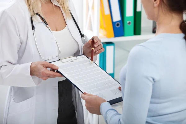 Femmina medico in possesso di modulo di domanda durante la consultazione paziente in ospedale — Foto Stock