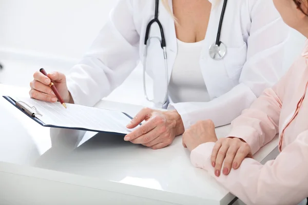 Médecin féminin tenant le formulaire de demande tout en consultant le patient à l'hôpital — Photo