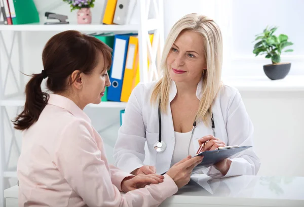Женщина-врач держит форму заявления во время консультации пациента — стоковое фото