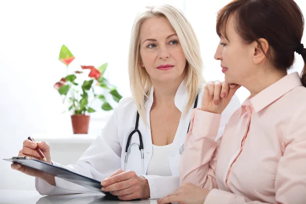 Female doctor holding application form while consulting patient — Stock Photo, Image