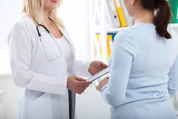 病院で患者を相談しながら申請書を保持している女性医師 — ストック写真