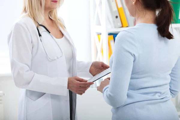 Médico femenino sosteniendo formulario de solicitud mientras consulta al paciente en el hospital — Foto de Stock