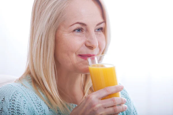 Woman drinking orange juice smiling. Beautiful middle aged Caucasian model face closeup. — Stock Photo, Image