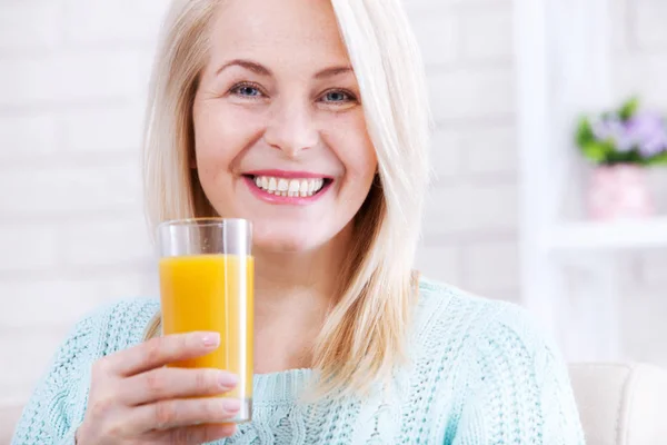 Woman drinking orange juice smiling. Beautiful middle aged Caucasian model face closeup. — Stock Photo, Image