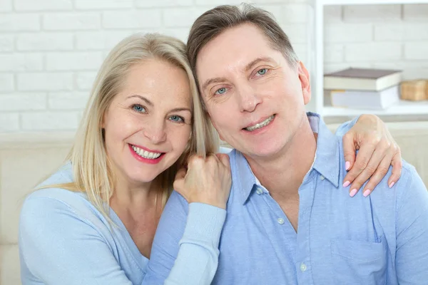 Middle aged couple relaxing on the couch smiling at camera at home in the living room — Stock Photo, Image