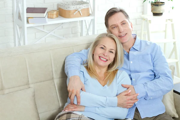 Middle aged couple relaxing on the couch smiling at camera at home in the living room — Stock Photo, Image