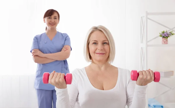 Picture of middle aged woman during rehabilitation in professional clinic. Rehabilitation, physiotherapy with dumbbells — Stockfoto