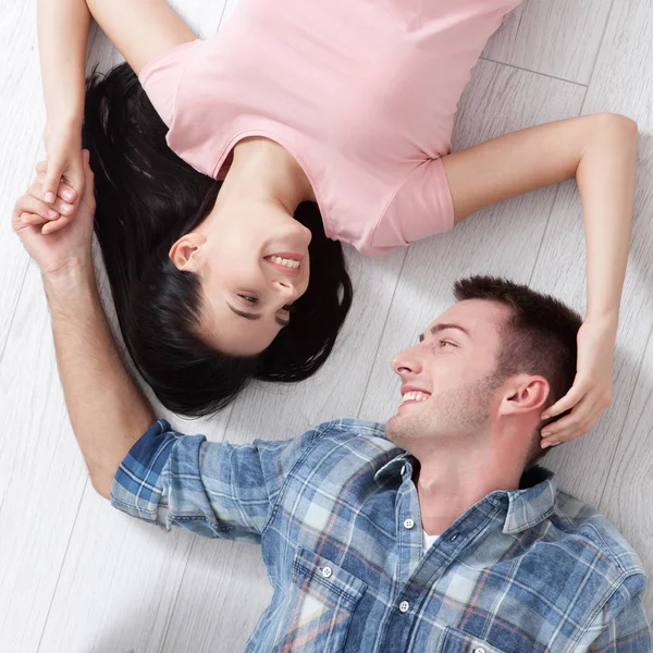 Ein glückliches junges Paar, auf dem Boden liegend, blickt sich an und träumt von Möbeln für eine neue Wohnung. Attrappe — Stockfoto