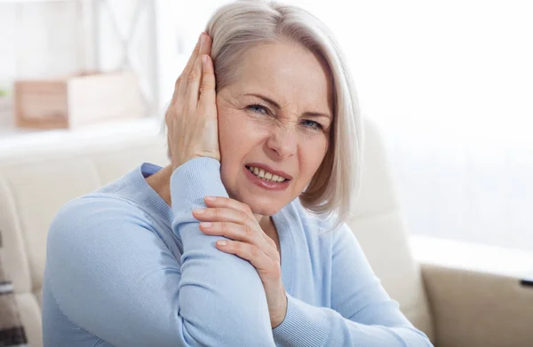 Tinnitus. Nahaufnahme Seitenprofil kranke Frau mit Ohrenschmerzen, die ihren schmerzenden Kopf berühren. — Stockfoto