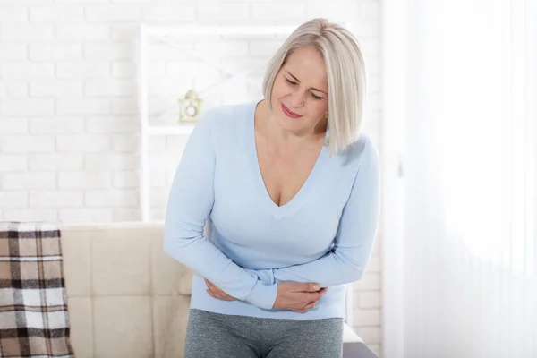 Donna di mezza età che soffre di dolore addominale mentre è a casa — Foto Stock