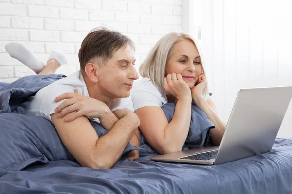 Piękna para amorów korzystająca z laptopa, na łóżku. Piękna kobieta i przystojny mężczyzna czytają wiadomości w Internecie. Związek pojęciowy. — Zdjęcie stockowe