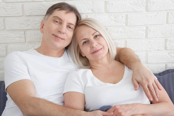 Senior couple at home. Handsome old man and attractive old woman are enjoying spending time together while lying in bed. — Stockfoto