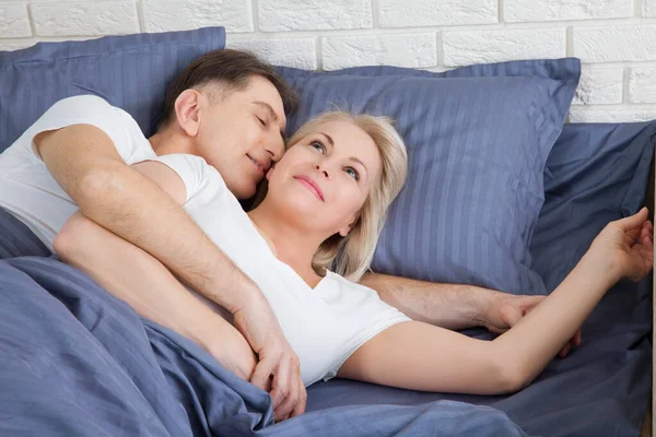 Starší pár doma. Hezký starý muž a atraktivní stará žena se těší trávit čas spolu, zatímco leží v posteli. — Stock fotografie
