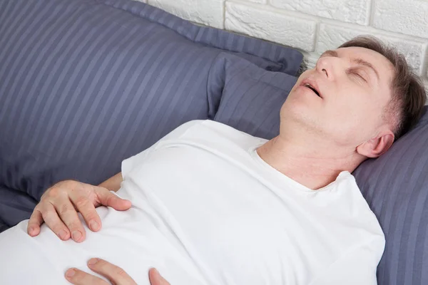 Man snoring because of sleep apnea lying in the bed