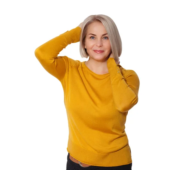 Blondine mittleren Alters posiert emotional in einem Studio. Glückliche Frau in gelbem hellen Pullover auf weißem Hintergrund — Stockfoto