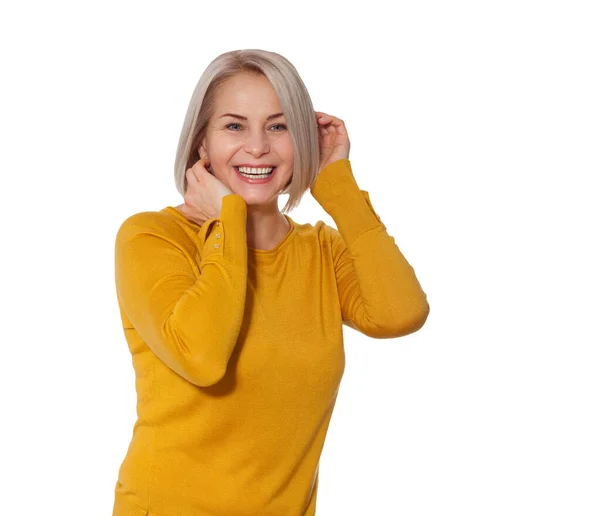 Középkorú szőke, érzelmileg pózol egy stúdióban. Boldog nő sárga fényes pulóver fehér háttér — Stock Fotó