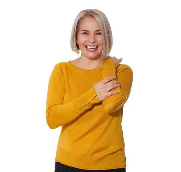 Bionda di mezza età emotivamente in posa in uno studio. Donna felice in maglione giallo brillante su sfondo bianco — Foto Stock