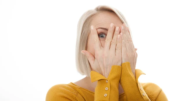 Nieuwsgierige vrouw bedekt het gezicht met de handen gluren spioneren oog op witte studiomuur, grappige vrouw voelt angst verlegen verbergen kijken naar camera door vingers geïsoleerd op witte lege achtergrond — Stockfoto