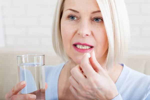 Medicina, cuidado de la salud y el concepto de las personas, primer plano de la mujer de mediana edad que toma en píldora Imagen de stock