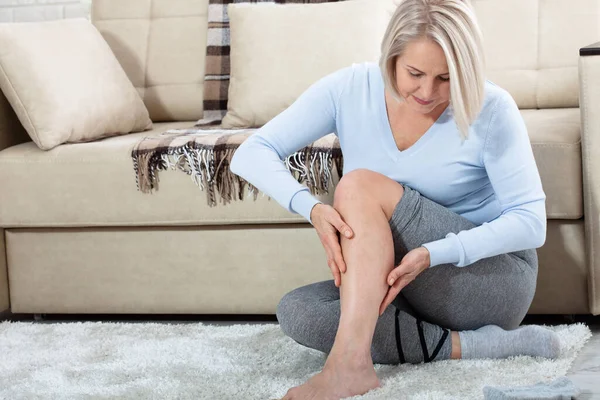 Kobieta w średnim wieku cierpiąca na ból nóg w domu, zbliżenie. Pojęcie urazu fizycznego. — Zdjęcie stockowe