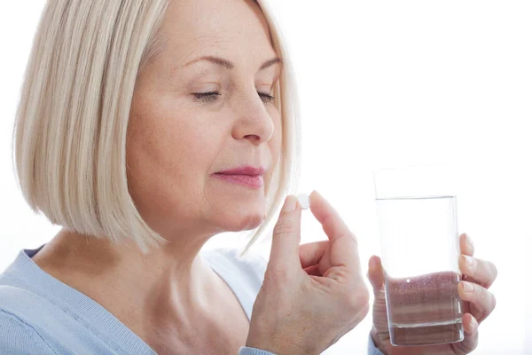 Medicina, cuidado de la salud y el concepto de las personas, primer plano de la mujer de mediana edad que toma en píldora Imágenes de stock libres de derechos