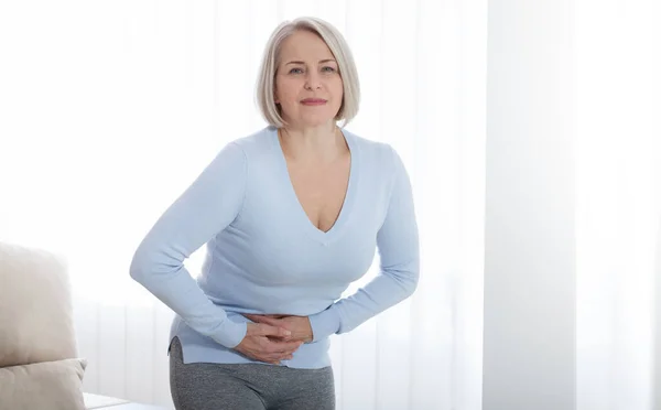 Mulher de meia-idade que sofre de dor abdominal em casa — Fotografia de Stock