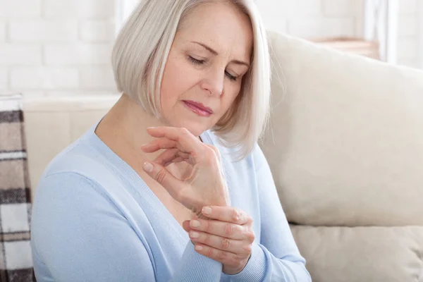 Frau massiert ihre arthritische Hand und ihr Handgelenk — Stockfoto