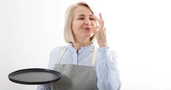 Женщина-повар показывает знак "вкусно". Женщина-шеф-повар в форме с идеальной вывеской, держащей пустую тарелку. Шеф-повар, повар или пекарь. Готовить со вкусом одобрение жест. Mock up . — стоковое фото