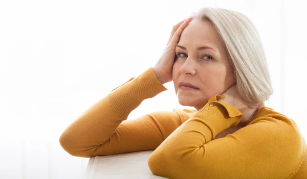 Woman suffering from stress or a headache grimacing in pain as she holds the back of her neck with her other hand to her temple, with copyspace. Concept photo with indicating location of pain. — Stockfoto