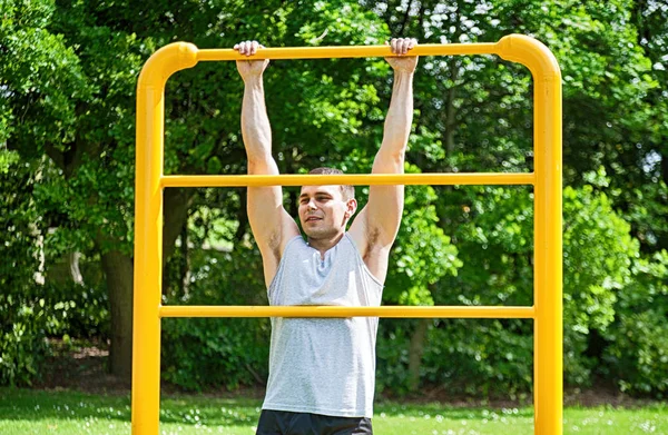 Man pulling up on the railing, on the outside gym