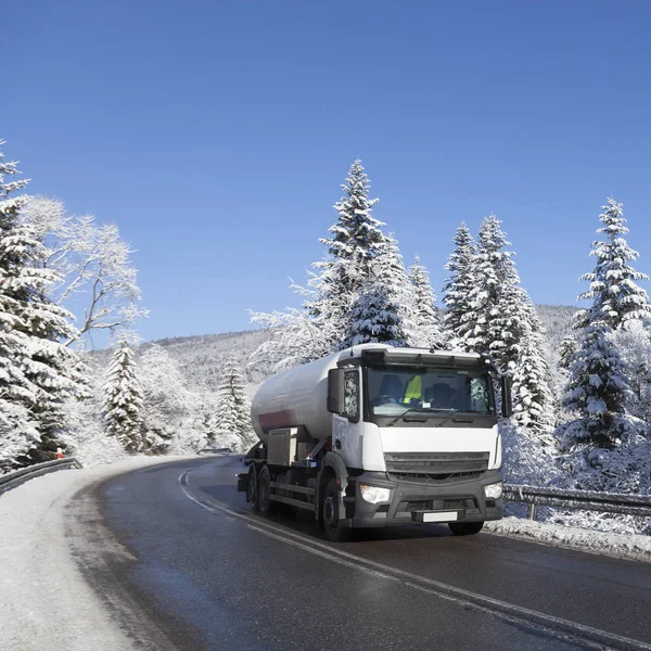 Tanker on an asphalt road among snow-covered trees. Nature in winter.