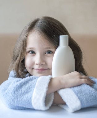 Kameraya bakarak farklı beyaz güzellik tuvalet malzemeleri onun elinde tutmak sevimli küçük kız. Bebek banyo, hijyen aksesuar. Kozmetik ürünleri kümesi. Köpükler, şampuan için kozmetik paket koleksiyonu